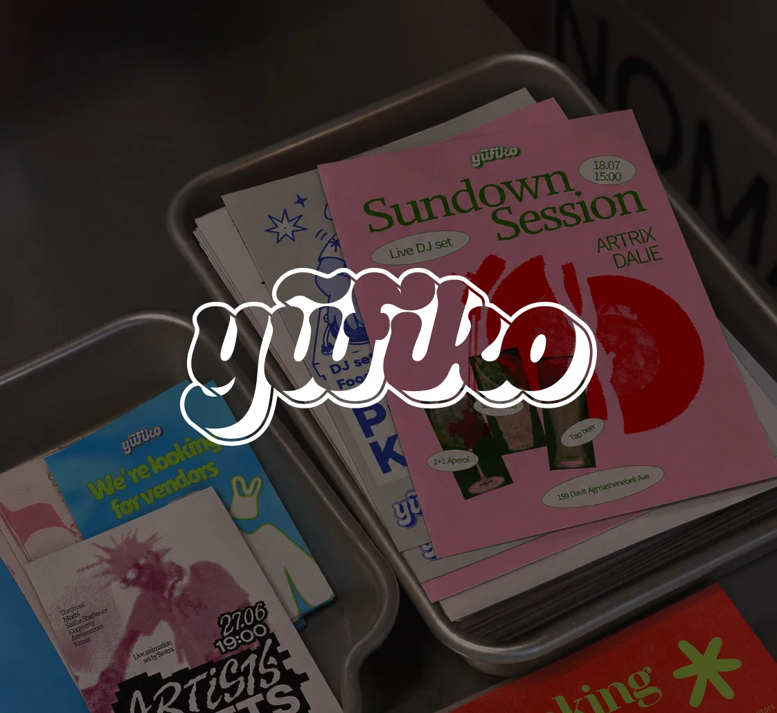 Yufiko logotype over printed flyers stacked in metal trays